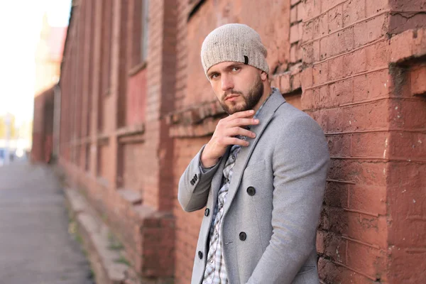 La vie urbaine. Jeune homme élégant en manteau gris et chapeau debout dans la rue dans la ville . — Photo