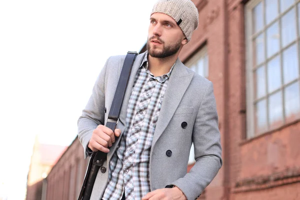 La vie urbaine. Jeune homme élégant en manteau gris et chapeau marchant dans la rue dans la ville . — Photo