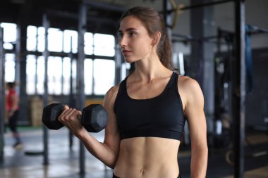 Spor salonunda kaslarını çalıştıran kaslı fit bir kadın..