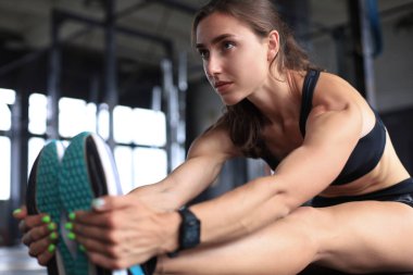 Spor salonunda esneyen genç bir kadın..