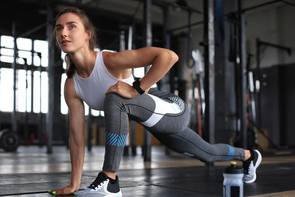 Young sporty woman stretching at the gym. — Stock Photo, Image