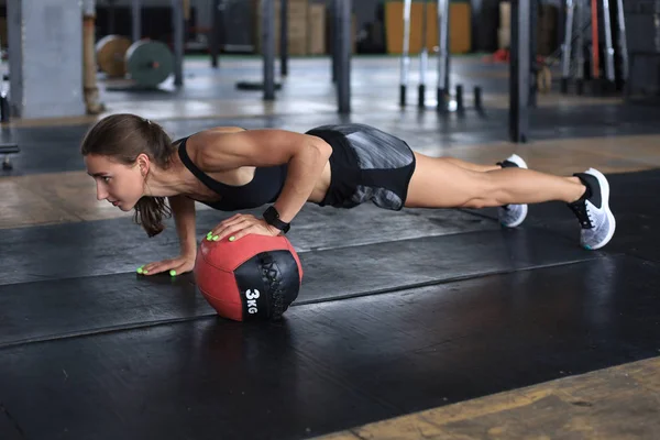 Formda ve kaslı bir kadın spor salonunda ilaç topuyla egzersiz yapıyor.. — Stok fotoğraf