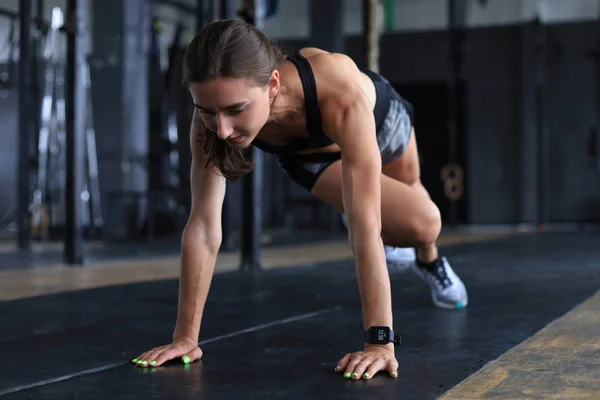Retrato de una mujer musculosa haciendo tablones en el suelo del gimnasio . — Foto de Stock