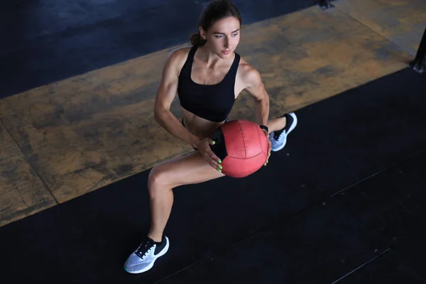 Visão superior da mulher apta e musculosa se exercitando com bola de remédio no ginásio. — Fotografia de Stock