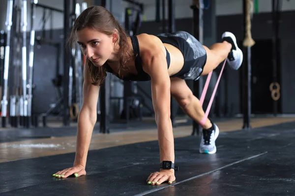 Mulher muscular em uma posição de prancha use chiclete fitness . — Fotografia de Stock