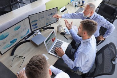 Formalite içinde çalışan bir grup modern iş adamı ofiste çalışırken borsa verilerini analiz ediyorlar..