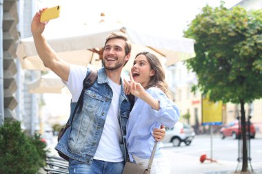Güzel, genç bir çift şehrin sokaklarında yürüyor, selfie çekerken sarılıyorlar..