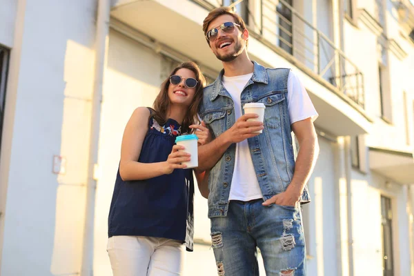 Egy gyönyörű boldog pár képe nyári ruhában, mosolyogva és egymás kezét fogva sétálva a város utcáin.. — Stock Fotó