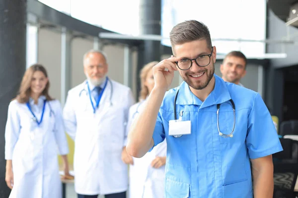 Glimlachende arts houdt tablet voor zijn medische team. — Stockfoto
