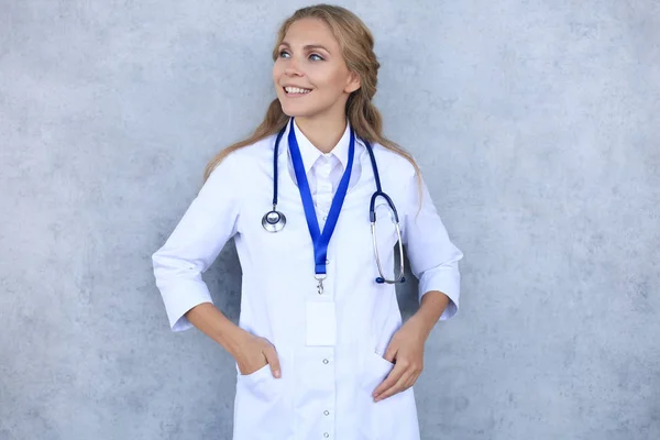 身穿白色制服外套和听诊器的快乐微笑的女医生，与灰色背景隔离. — 图库照片