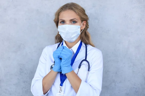 Médica feminina em máscara médica com estetoscópio olhando para a câmera isolada sobre fundo cinza . — Fotografia de Stock