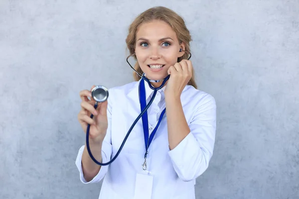 Glücklich lächelnde Ärztin in weißem Uniformmantel und Stethoskop, isoliert vor grauem Hintergrund. — Stockfoto