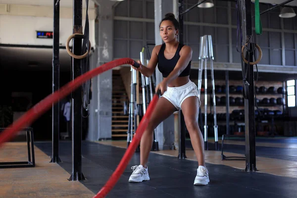 Fit woman using battle ropes during strength training at the gym. — Stock Photo, Image