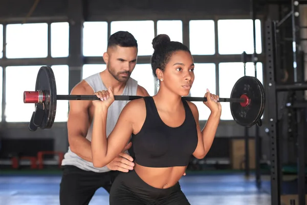 Hombre y mujer con los músculos de flexión de la barra en el gimnasio. — Foto de Stock