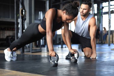 Sportif bir kadın spor salonunda şınav çekiyor, erkek arkadaşı onu izliyor..