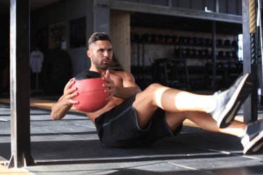 Spor salonunda tıp topu ile egzersiz fit ve kaslı adam.