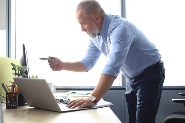 Елегантний зрілий бізнесмен аналізує дані під час роботи в офісі . — стокове фото