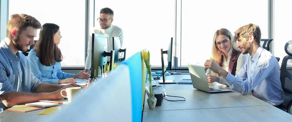 Jóvenes colegas modernos en ropa casual inteligente trabajando juntos mientras pasan tiempo en la oficina creativa . —  Fotos de Stock