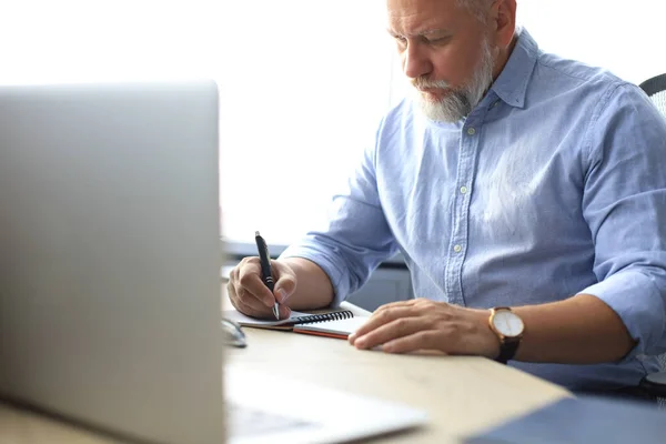 Gammal affärsman tittar och analyserar dokument i sitt moderna kontor på jobbet. — Stockfoto