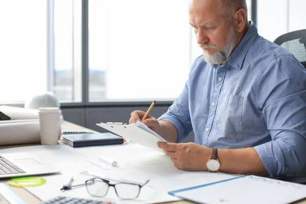 Snygg mogen arkitekt ritar något när han arbetar på kontoret. — Stockfoto