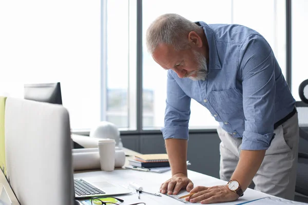 Gut aussehender, reifer Architekt, der im Büro etwas zeichnet. — Stockfoto