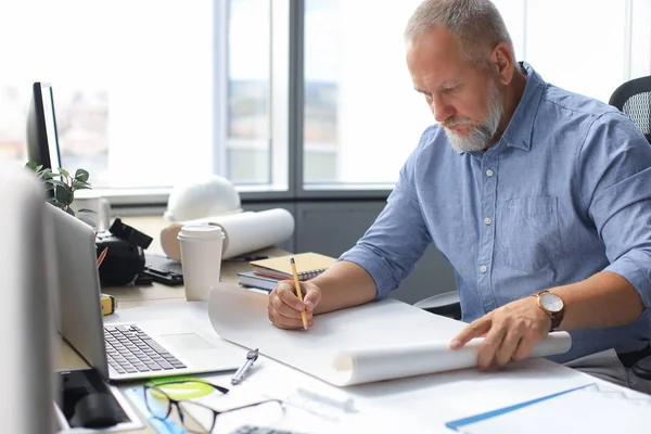 Gut aussehender, reifer Architekt, der im Büro etwas zeichnet. — Stockfoto