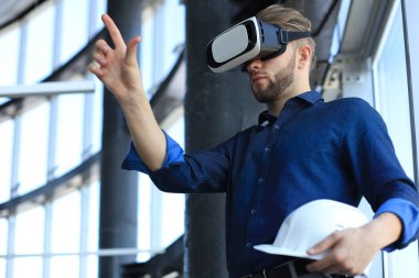 Elinde hardhat olan ve yeni bir binada Vr kulaklık takan bir mühendisin fotoğrafı. Dünyayı görme ve deneyimleme şeklinizi değiştirin.