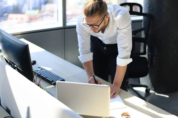 Fiatal modern üzletember adatok elemzése laptoppal, miközben dolgozik az irodában. — Stock Fotó