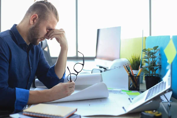 Müder junger Mann arbeitet im Büro mit Papieren — Stockfoto