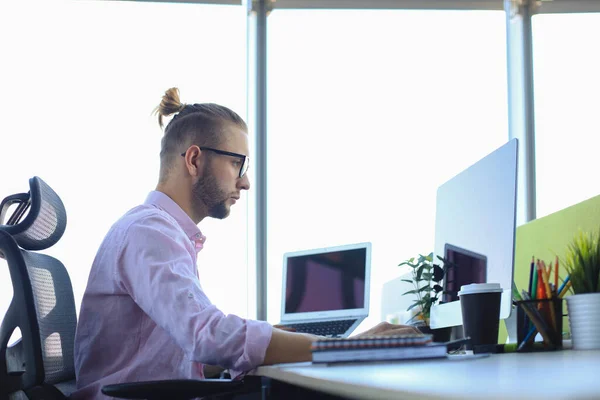 Tankeväckande ung affärsman i skjorta arbetar med hjälp av datorn när du sitter på kontoret. — Stockfoto