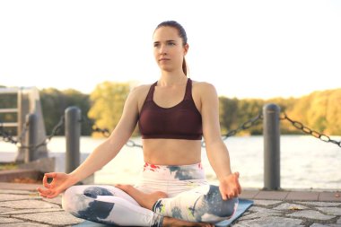 Young pretty woman doing yoga exercises in the park.