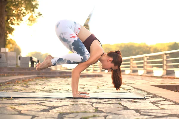 Atlético forte mulher praticando difícil ioga pose ao ar livre . — Fotografia de Stock