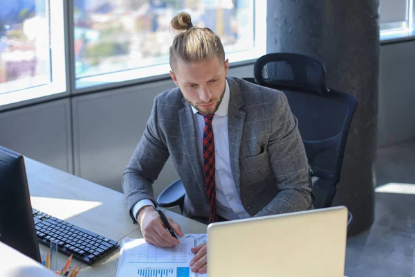 Joven hombre de negocios moderno que trabaja con el ordenador portátil mientras está sentado en la oficina. — Foto de Stock