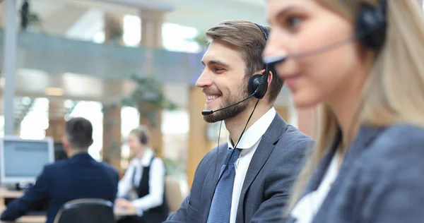 Portret van callcenter medewerker vergezeld door zijn team. Lachende klant support operator aan het werk. — Stockfoto