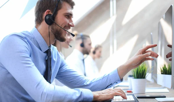 Porträt eines Callcenter-Mitarbeiters in Begleitung seines Teams. Lächelnder Kundenbetreuer bei der Arbeit. — Stockfoto