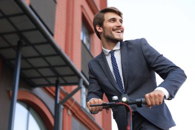 Şehir caddesinde elektrikli scooter kullanan genç iş adamı. Modern ve ekolojik ulaşım konsepti