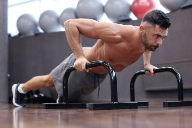 Spor salonunda barlar ile yatay şınav yapıyor fit ve kaslı adam