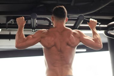 Fit ve kaslı adam bir spor salonunda yatay bar üzerinde çekerek