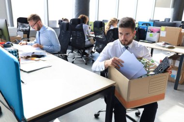 Üzgün işçi ofis malzemelerini yanında götürüyor.