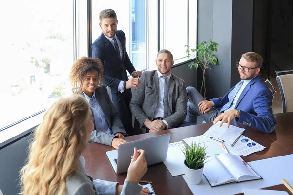 フォーマルウェアを着た若い現代人のグループは 現代のオフィスで働きながら 笑顔で何かを議論します — ストック写真