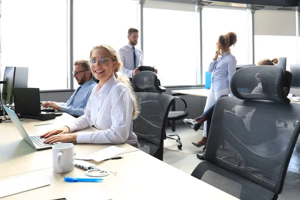 背景にコルゲを持つ現代のオフィスでラップトップに取り組むフォーマルウェアの喜びのビジネスウーマン — ストック写真