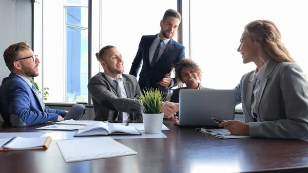 Groupe de jeunes gens modernes en tenue de cérémonie souriant et discutant de quelque chose tout en travaillant dans le bureau moderne — Photo