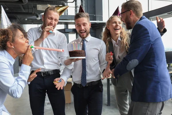 Счастливая деловая команда с праздничным тортом встречает коллегу на корпоративной вечеринке — стоковое фото