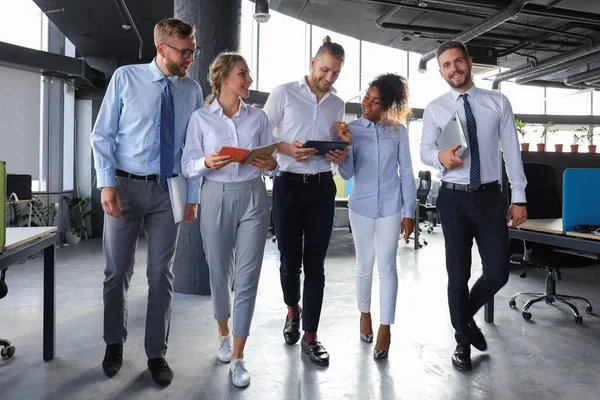 Moderne Geschäftsleute diskutieren über Geschäfte und lächeln beim Gang durch den Büroflur — Stockfoto