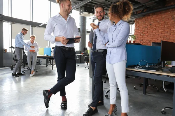 Grupo de empresarios modernos están hablando y sonriendo mientras están de pie en el pasillo de la oficina — Foto de Stock