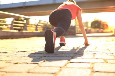 Açık havada koşarken başlangıç çizgisinde duran spor giyim genç kadının üst arka görünümü