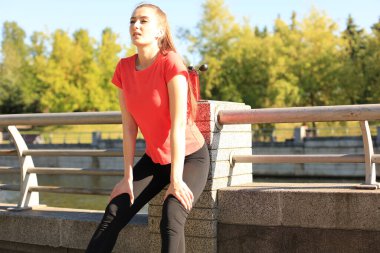 Spor giyim çekici genç kadın açık havada otururken bir mola