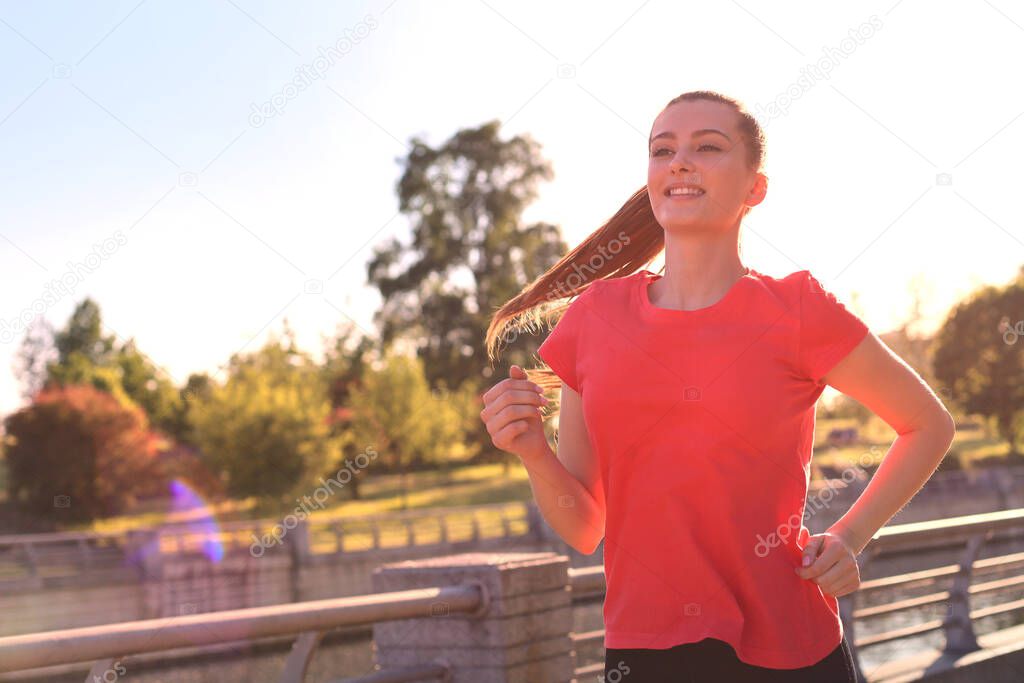 Beautiful young woman in sports clothing running while exercising outdoors