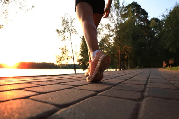 靴の上の道路上を走るランナーの足 日没や日の出の屋外 — ストック写真