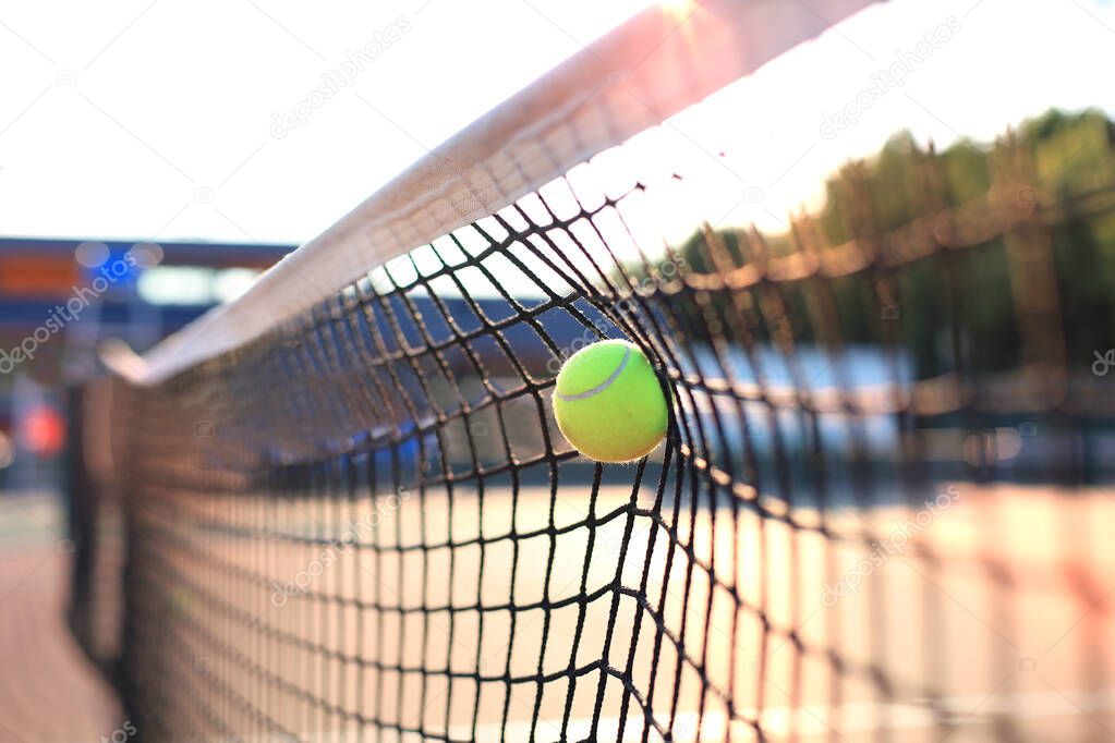 Bright greenish yellow tennis ball hitting the net